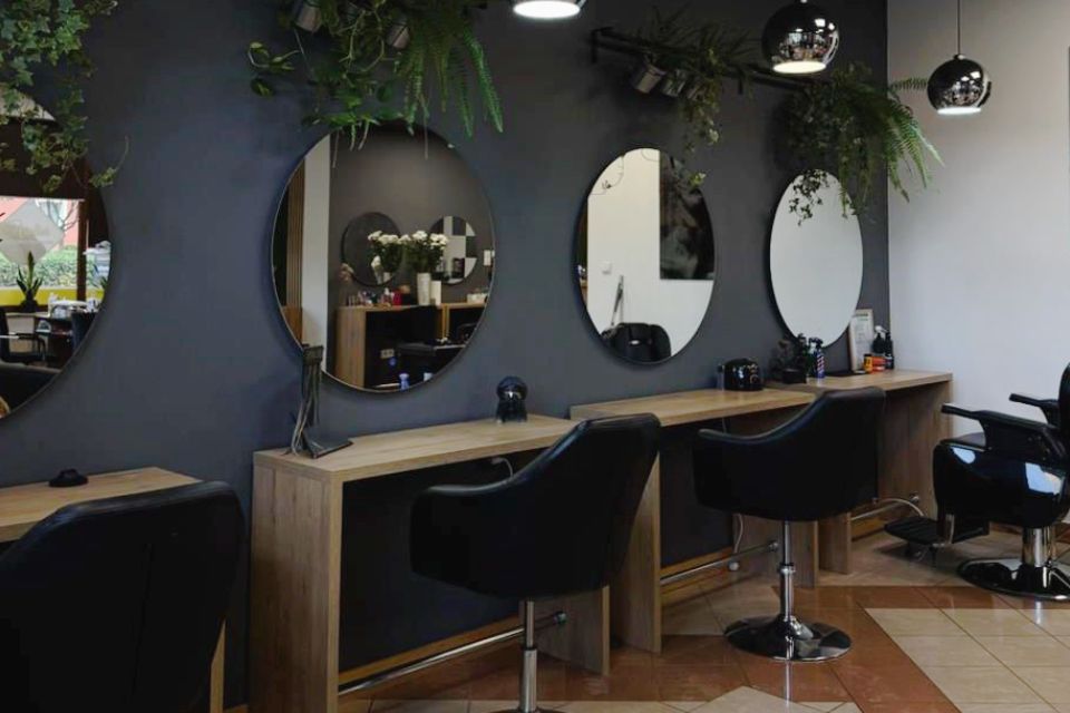 Wnętrze salonu Atelier — stanowiska fryzjerskie z okrągłymi lustrami